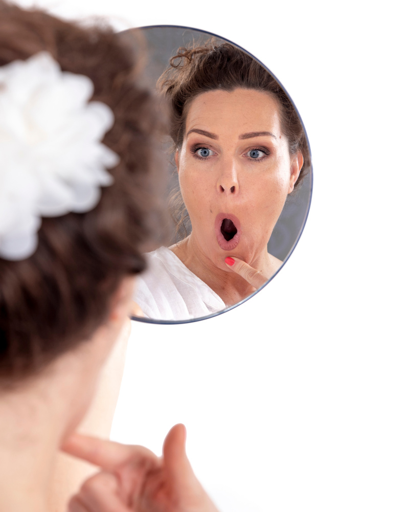 Middle-aged doing facial exercises in the mirror - face yoga