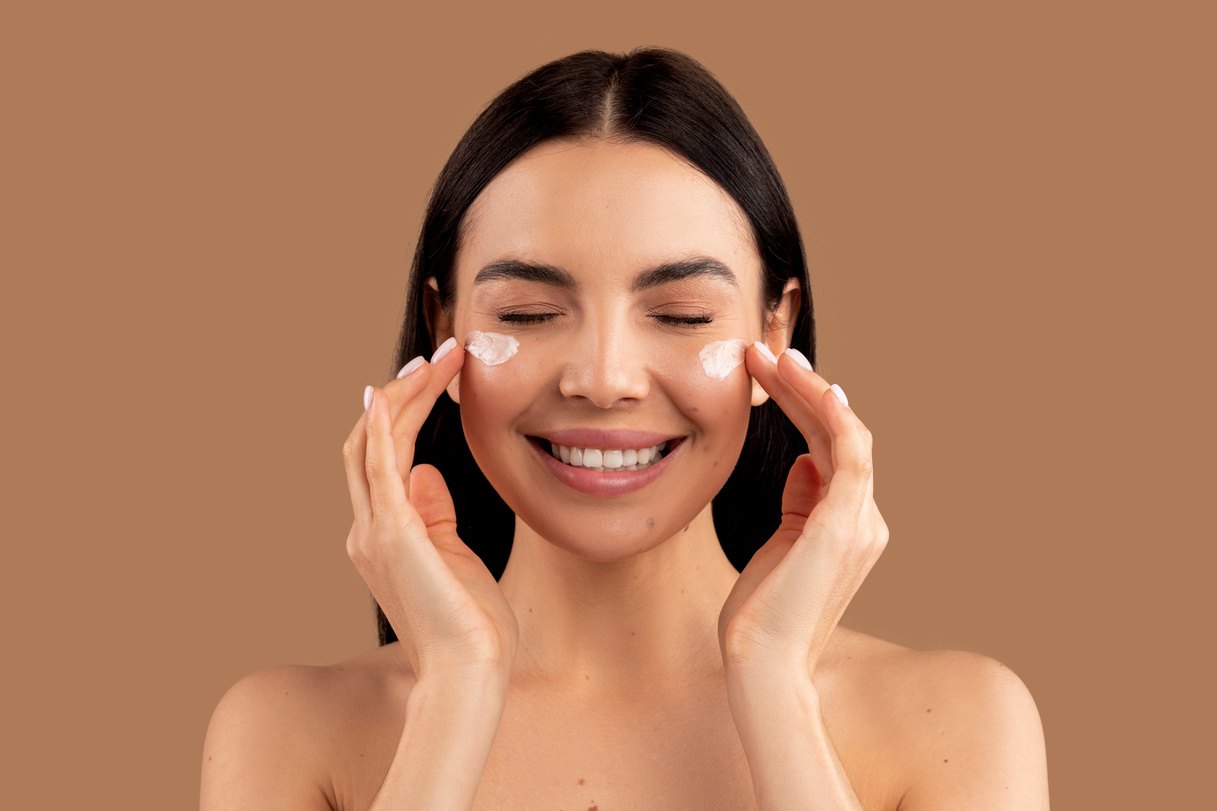 naked young woman using facial cream