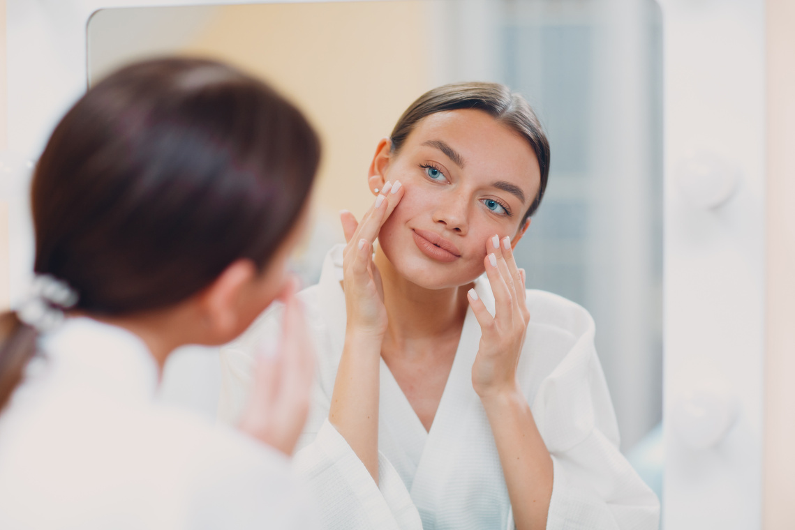 Young Caucasian Woman Doing Facebuilding Yoga Facial Gymnastics Self Lymph Facelift Massage at Home Mirror